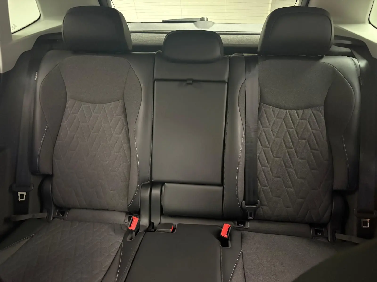 Vue intérieure des sièges arrière du Volkswagen Tiguan 2025, tissu noir avec motifs géométriques et ceinture de sécurité visible.