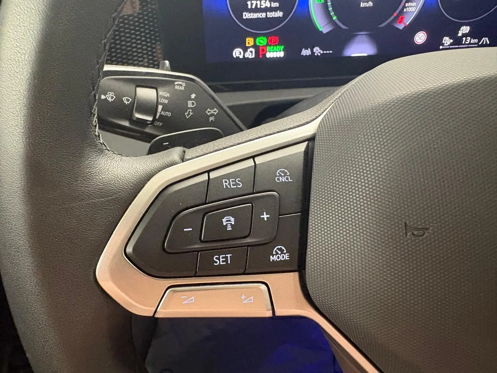 Gros plan sur le côté gauche du volant du Volkswagen Tiguan 2025, montrant les commandes de régulateur de vitesse et l'affichage numérique en arrière-plan.