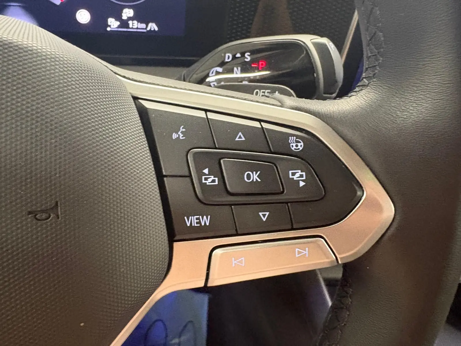 Gros plan sur le volant côté gauche du Volkswagen Tiguan 2025, avec commandes intégrées et indication de siège chauffant.