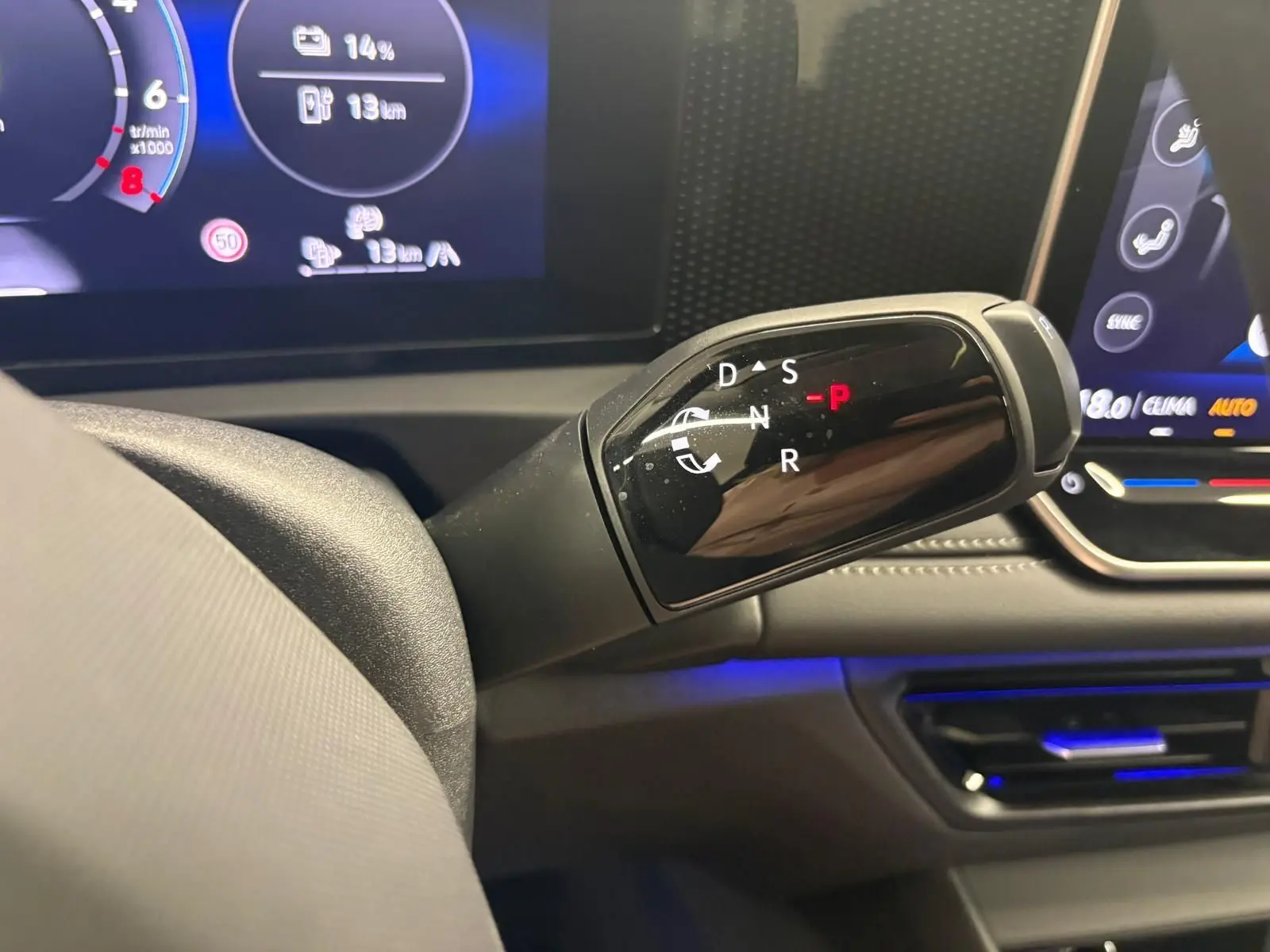 Gros plan sur le levier de vitesses automatique du Volkswagen Tiguan 1.5 eHybrid, avec tableau de bord numérique en arrière-plan.