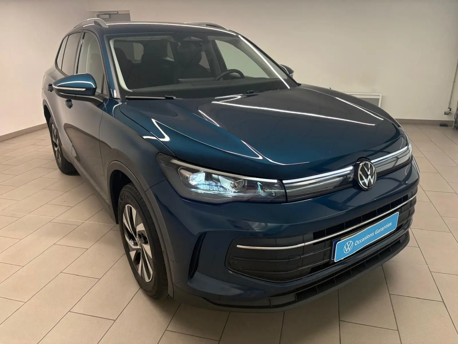 Volkswagen Tiguan 1.5 eHybrid en Nightshade Blue, vue 3/4 avant droit, intérieur visible, éclairage LED allumé.