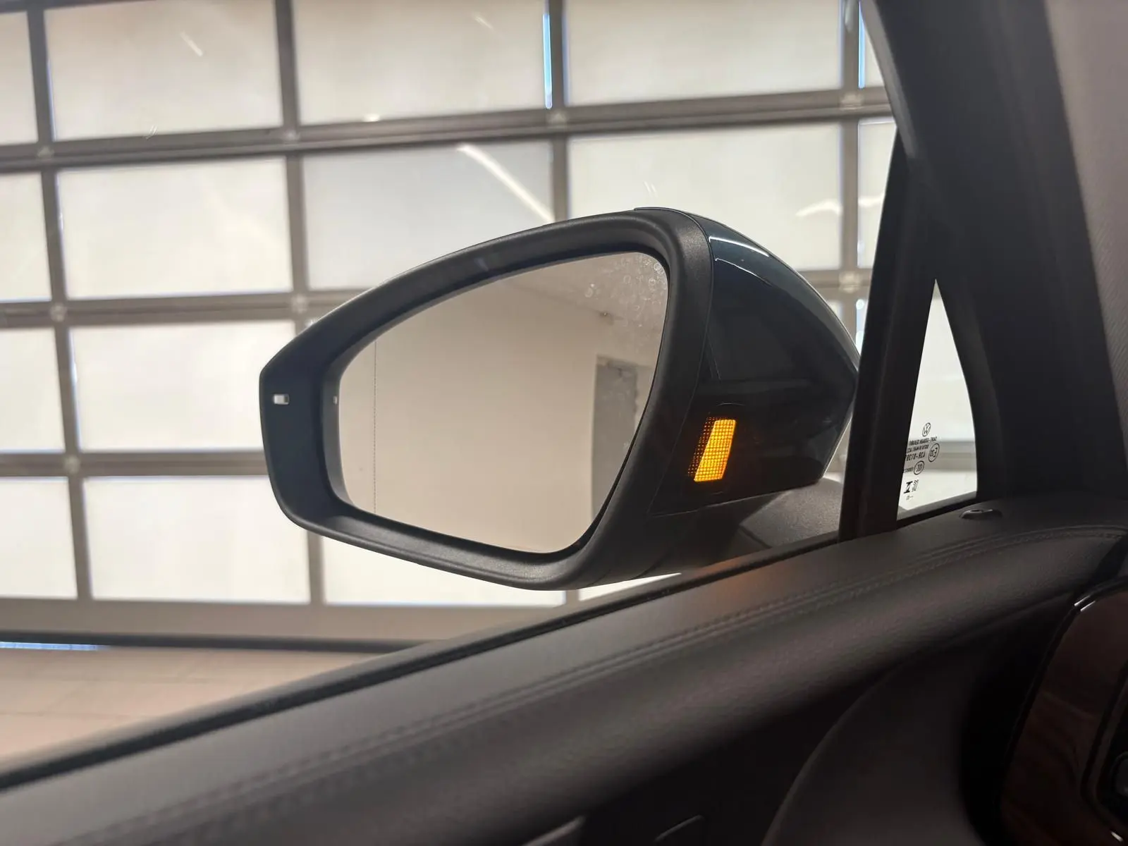 Rétroviseur extérieur droit du Volkswagen Tiguan 1.5 eHybrid Nightshade Blue avec clignotant orange allumé, vue intérieure.