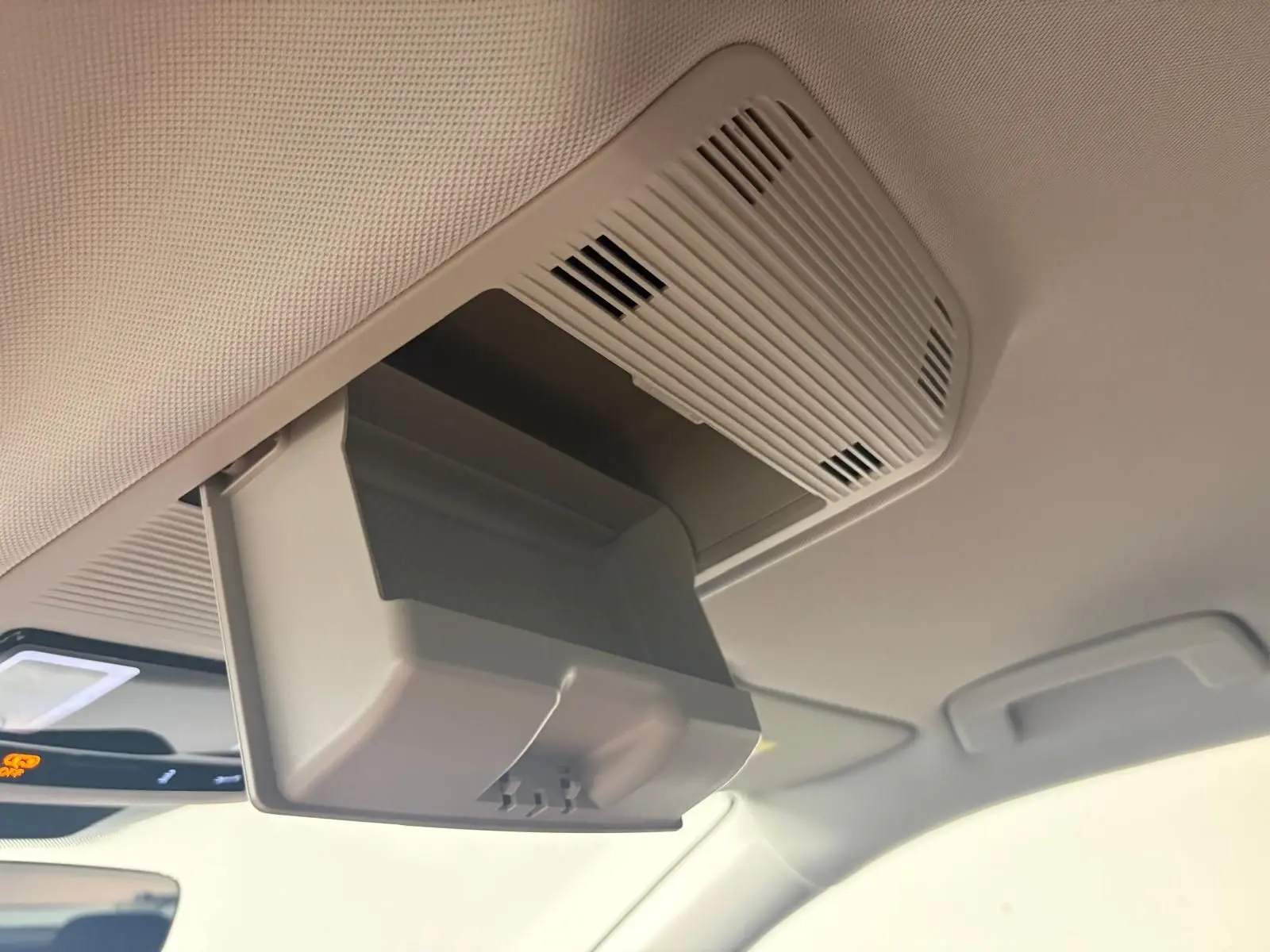 Détail du rangement lunettes ouvert sur le plafond intérieur d’un Volkswagen Tiguan 2025, finition claire.