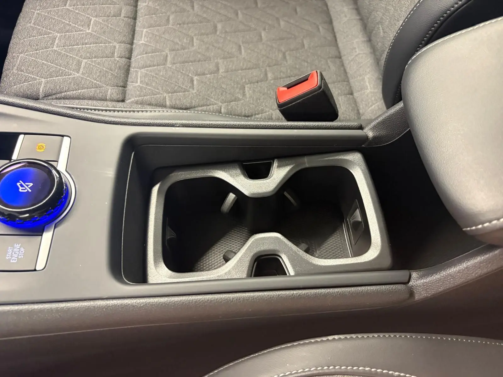 Gros plan sur la console centrale du Volkswagen Tiguan 2025, avec porte-gobelets et bouton rotatif bleu Nightshade Blue.