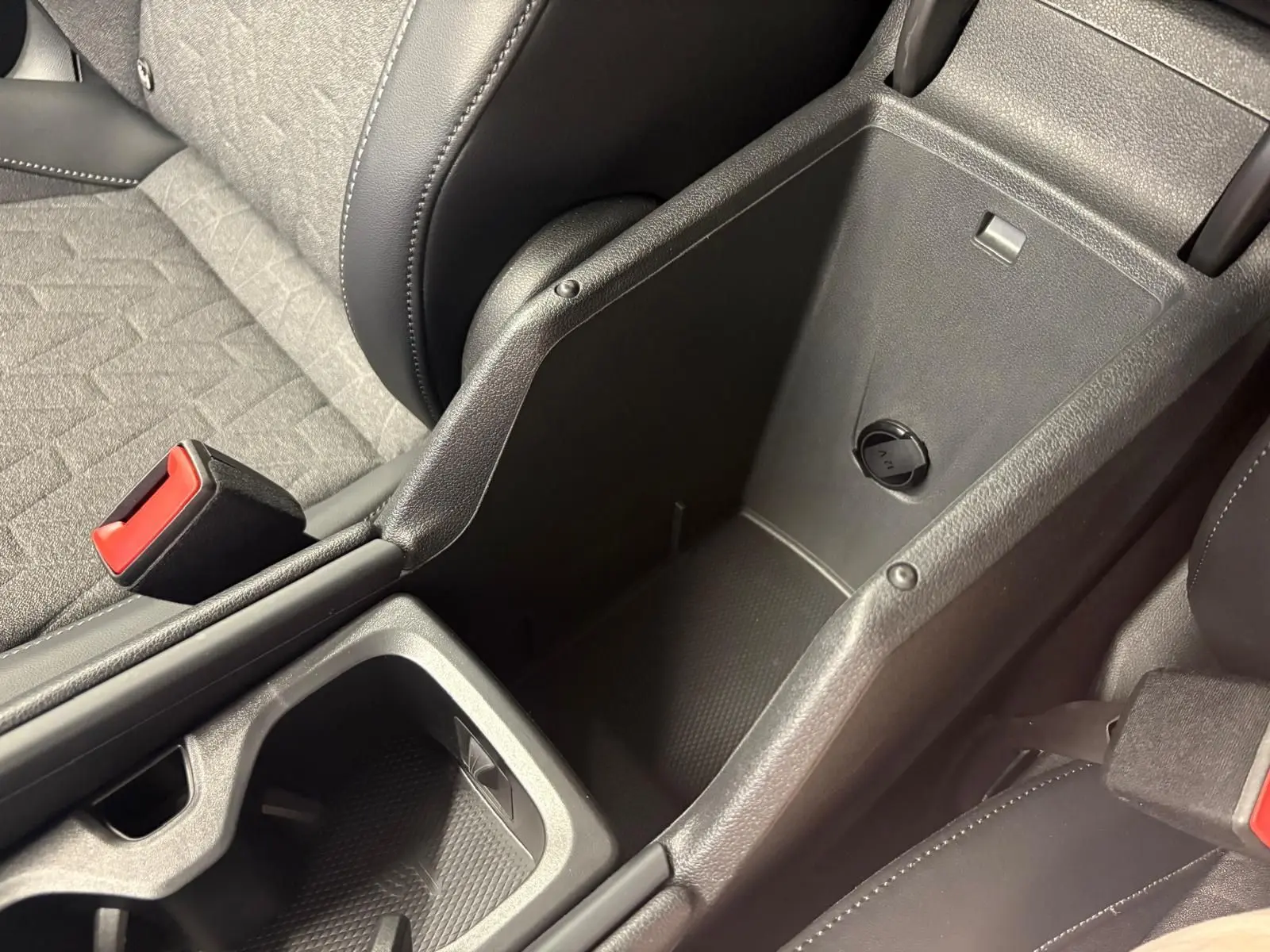 Vue rapprochée de la console centrale ouverte du Volkswagen Tiguan 2025, montrant le rangement intérieur et les sièges gris et noirs.