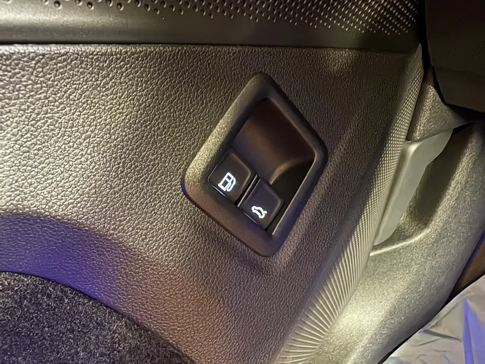Gros plan sur les boutons d'ouverture du réservoir et du coffre dans l'habitacle du Volkswagen Tiguan Nightshade Blue 2025.