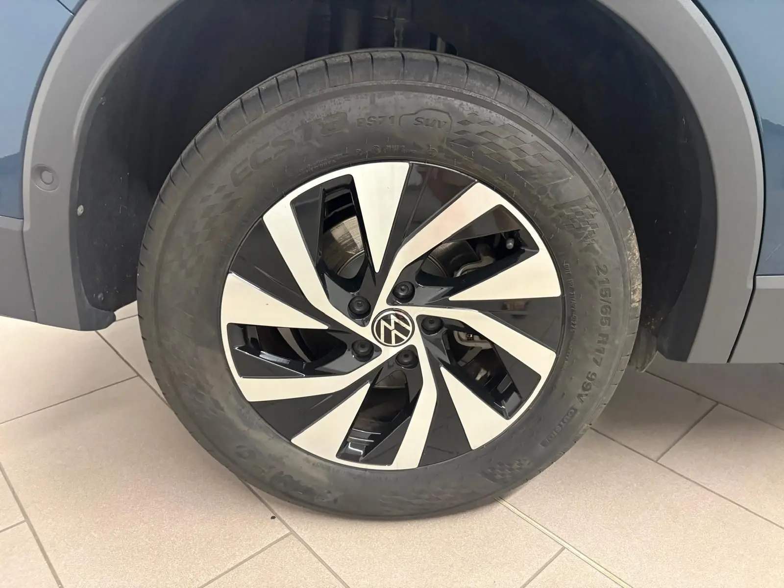 Gros plan sur la roue avant droite du Volkswagen Tiguan 1.5 eHybrid en Nightshade Blue avec jante alliage bicolore.