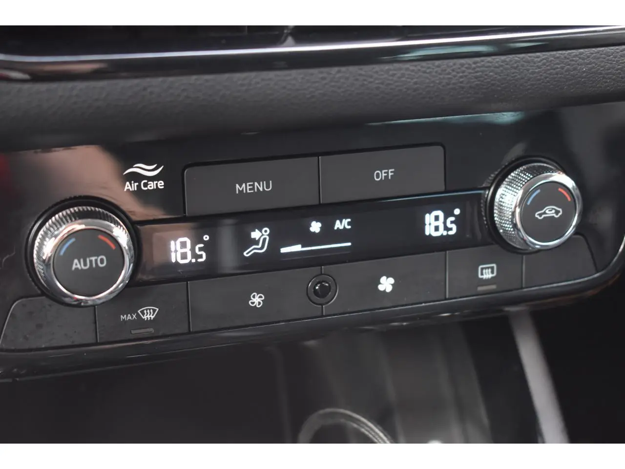 Gros plan sur la commande de climatisation automatique bi-zone noire avec affichage digital à 18,5°C dans une Skoda Scala blanche.