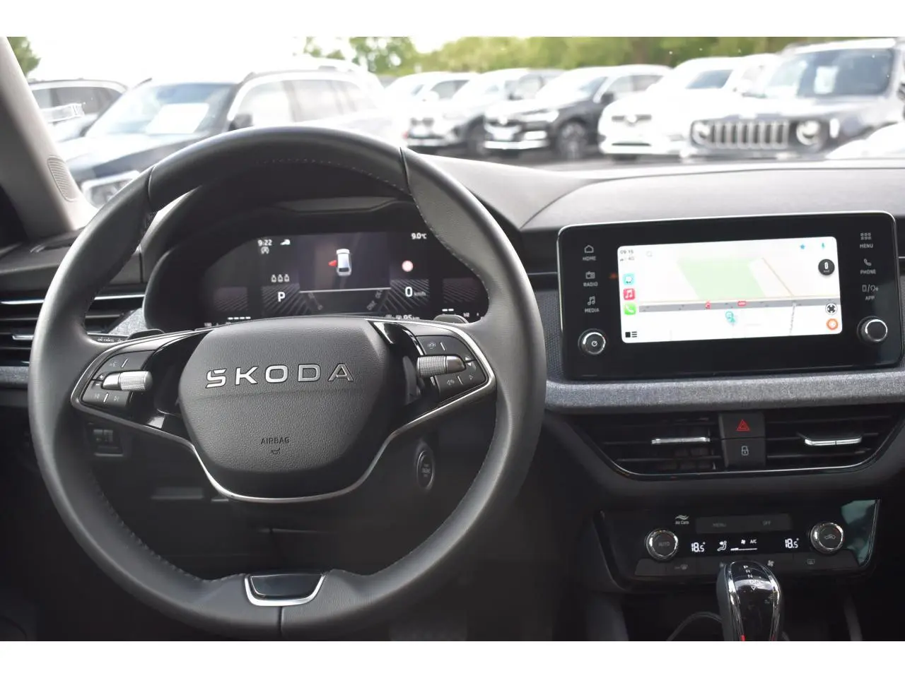 Vue intérieure centrée sur le volant SKODA et l'écran tactile du tableau de bord du SCALA blanc glacier 2025.