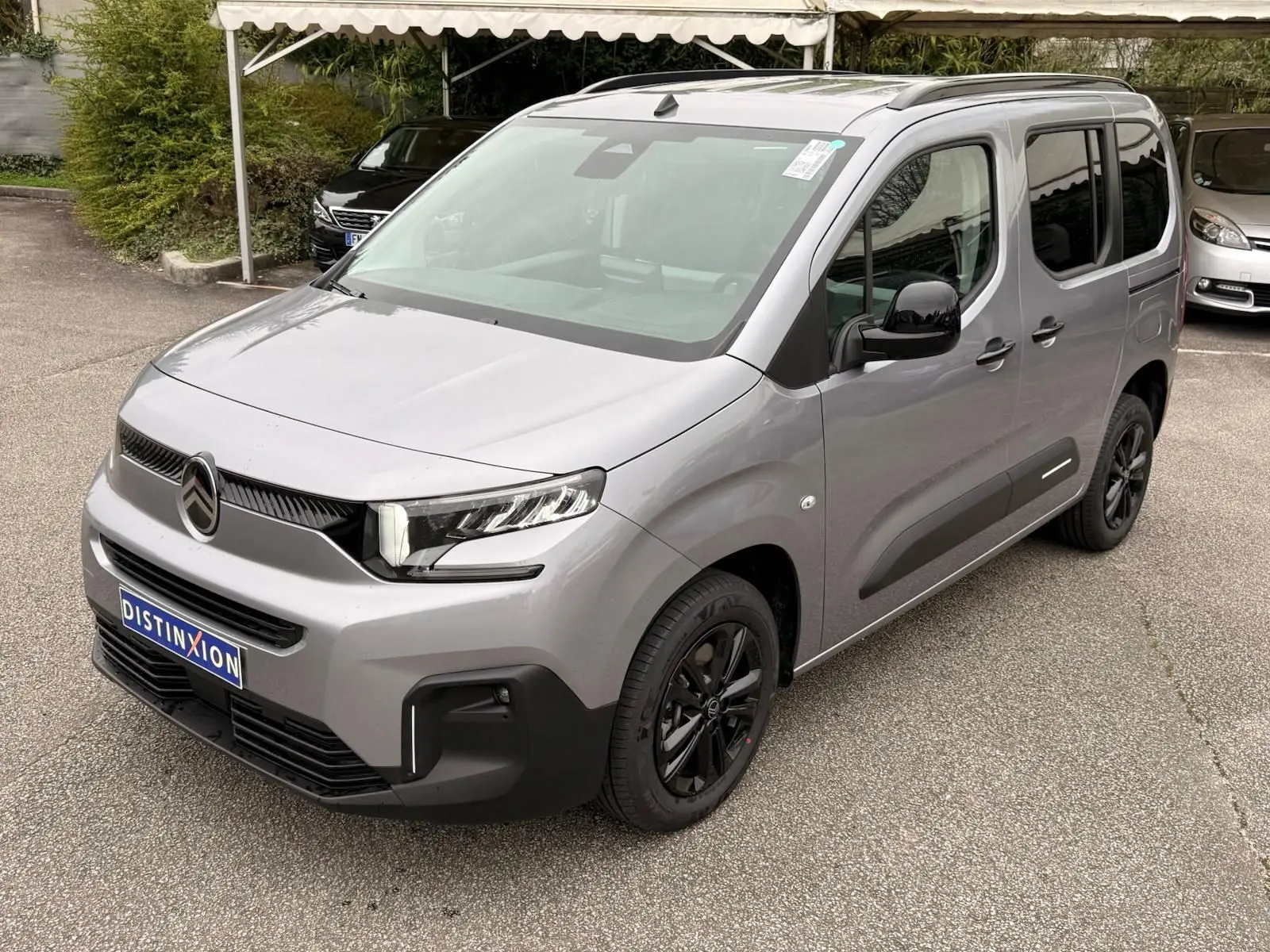 Citroën Berlingo gris Artense en 3/4 avant droit, avec jantes noires et détails noirs contrastants.