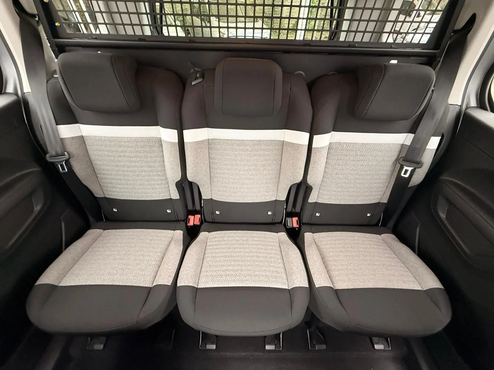 Vue intérieure sur la banquette arrière trois places du Citroën Berlingo 2025 avec sièges tissu gris clair et noir.