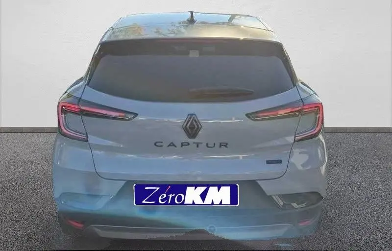 Vue arrière d'un Renault Captur E-Tech hybride gris Rafale avec toit gris, feux LED étirés et logo central visible.