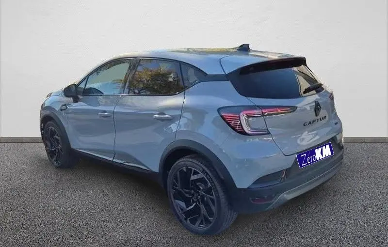 Vue 3/4 arrière droite d'un Renault Captur E-Tech hybride gris Rafale avec toit gris et jantes noires.
