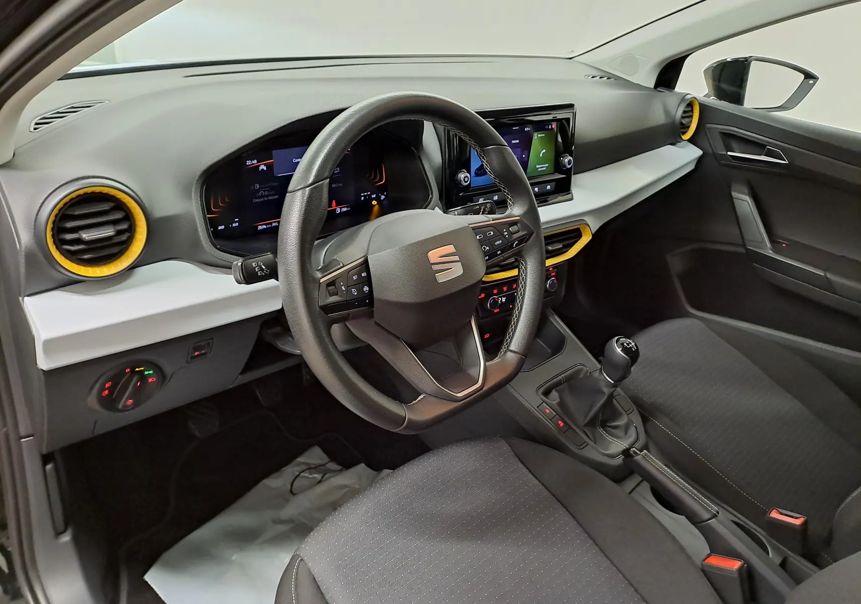 Vue intérieure côté conducteur de la SEAT Ibiza 2024 noir minuit, avec volant multifonction et détails jaunes autour des aérateurs.