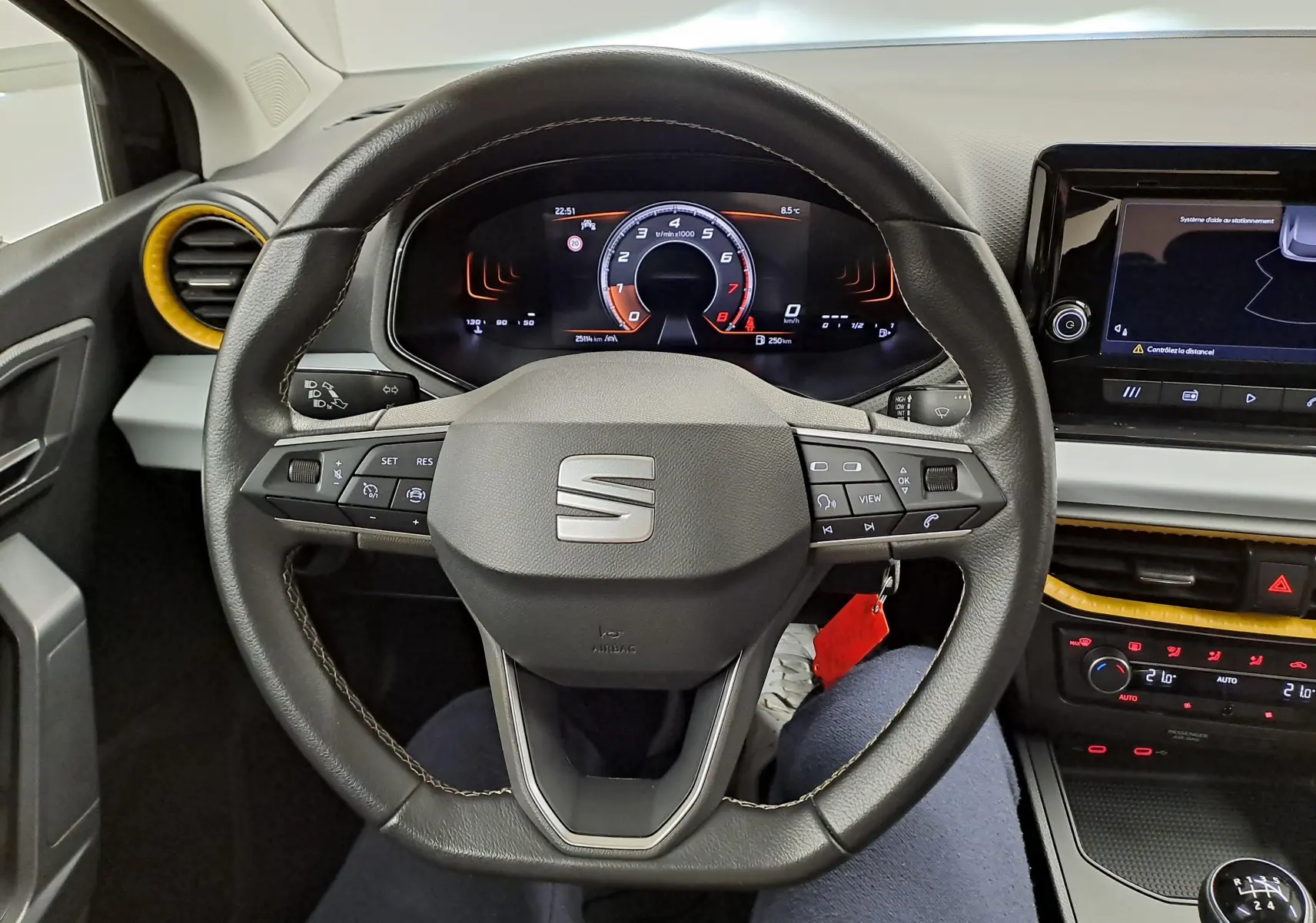 Vue intérieure centrée sur le volant de la SEAT Ibiza noir minuit 2024, avec tableau de bord numérique et détails jaunes autour des aérateurs.