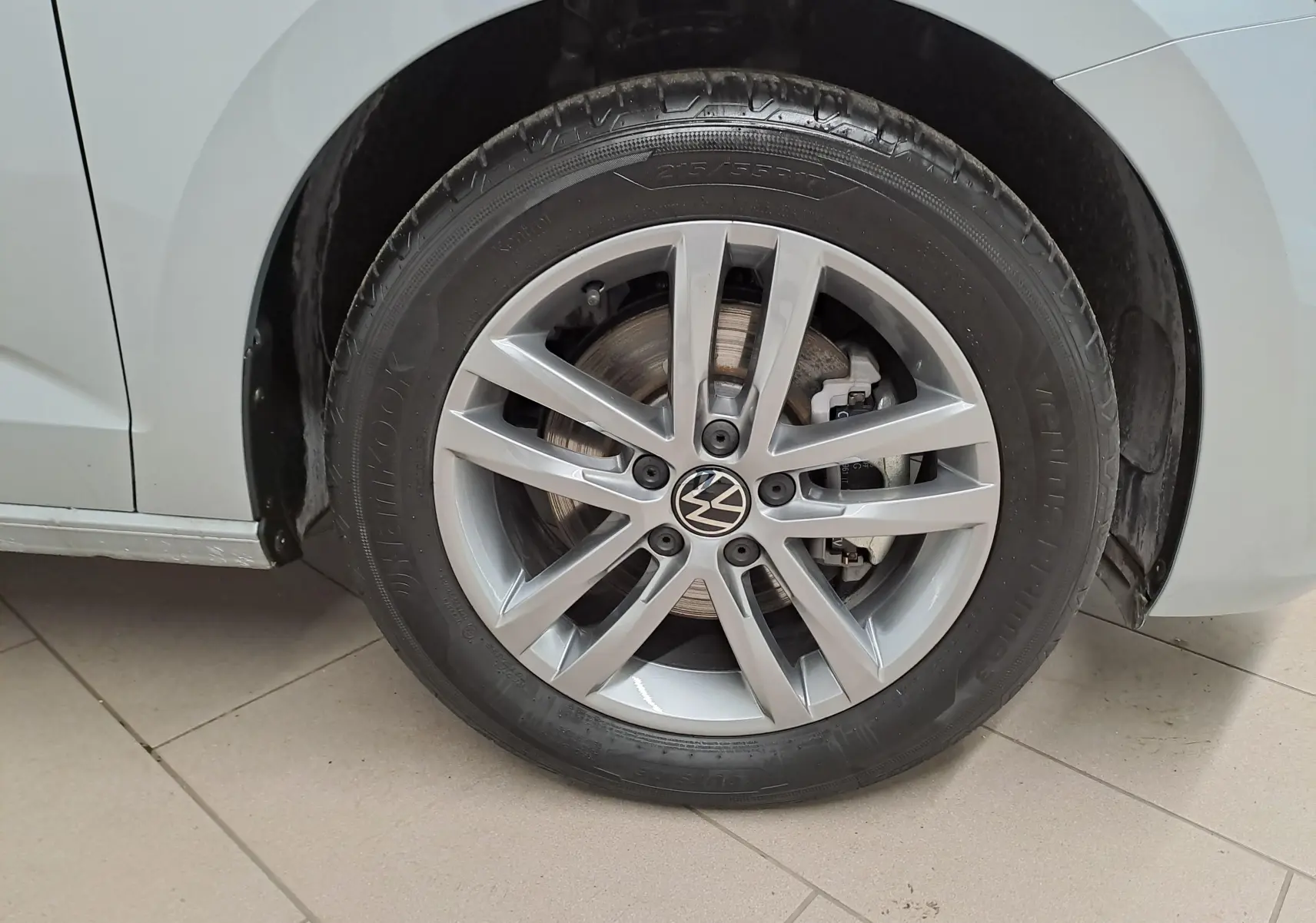 Gros plan sur la roue avant gauche argentée du Volkswagen Touran 2025 avec jante alliage et peinture métallisée Argent Dolomite.