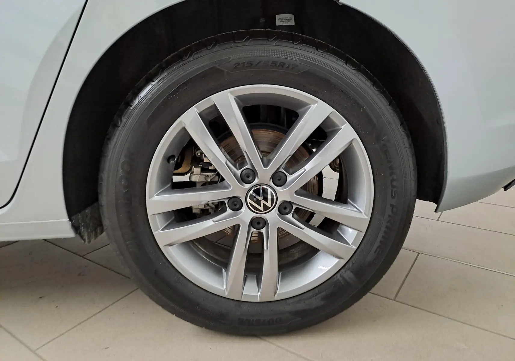 Gros plan sur la roue avant droite argentée du Volkswagen Touran 2025 avec jante alliage et peinture métallisée Argent Dolomite.