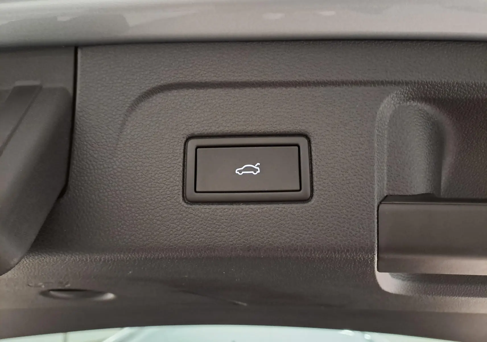 Bouton d'ouverture électrique du hayon sur la partie intérieure du coffre du Volkswagen Touran argent Dolomite.