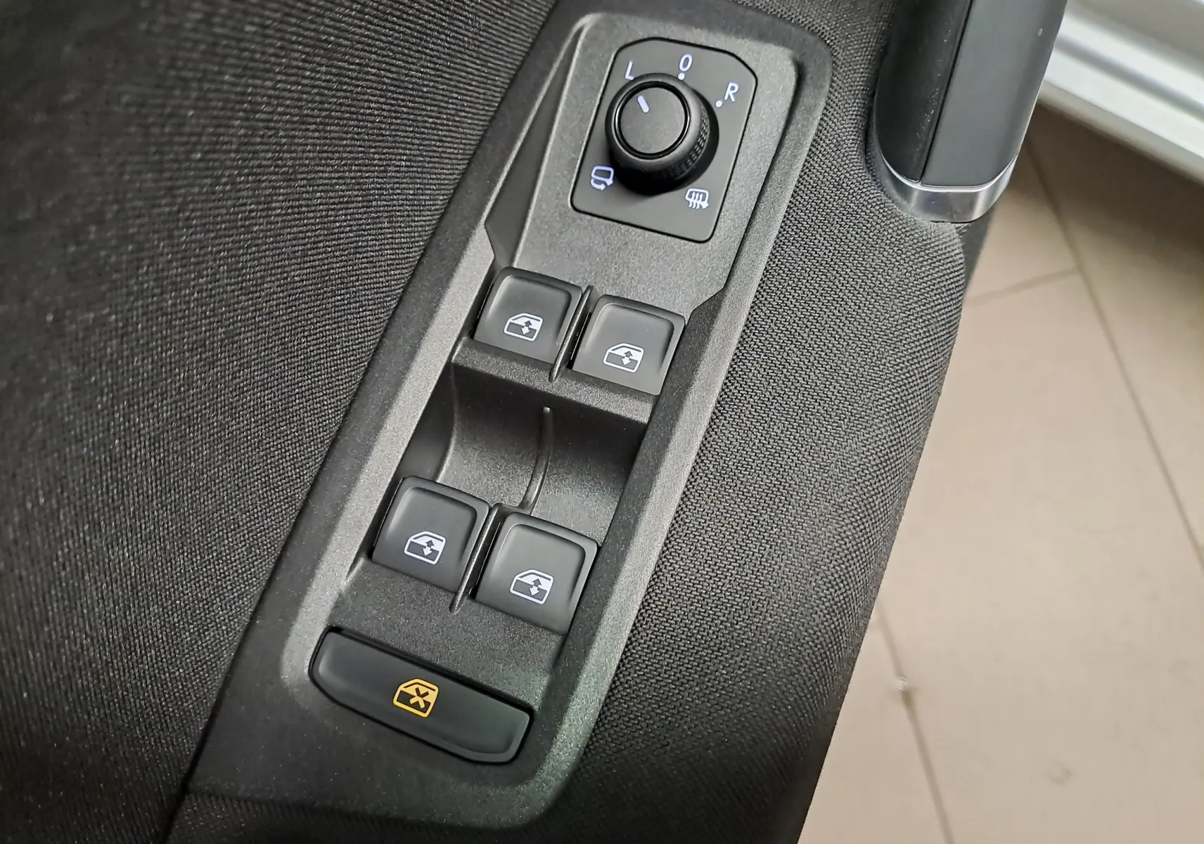 Gros plan sur les commandes des vitres électriques et rétroviseurs côté gauche d’un Volkswagen Touran 2025 Argent Dolomite.