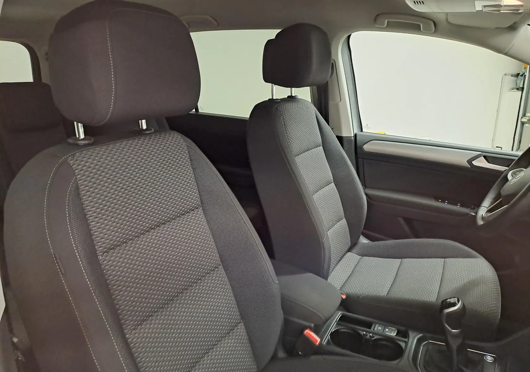 Vue intérieure côté droit du Volkswagen Touran 2025, sièges tissu gris foncé et levier de vitesse manuel visible.