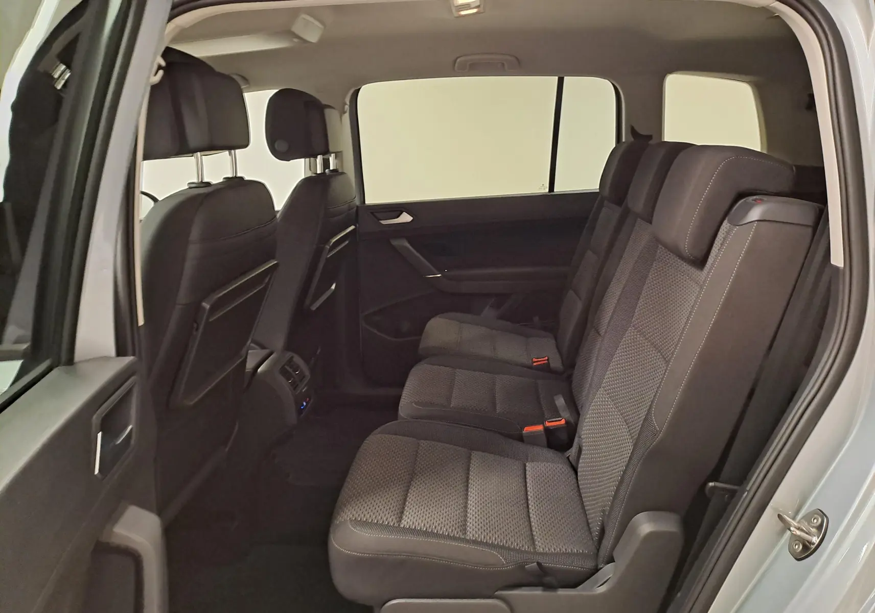 Vue intérieure côté droit du Volkswagen Touran 2025 argent Dolomite, montrant les sièges arrière en tissu noir et les appuie-têtes.