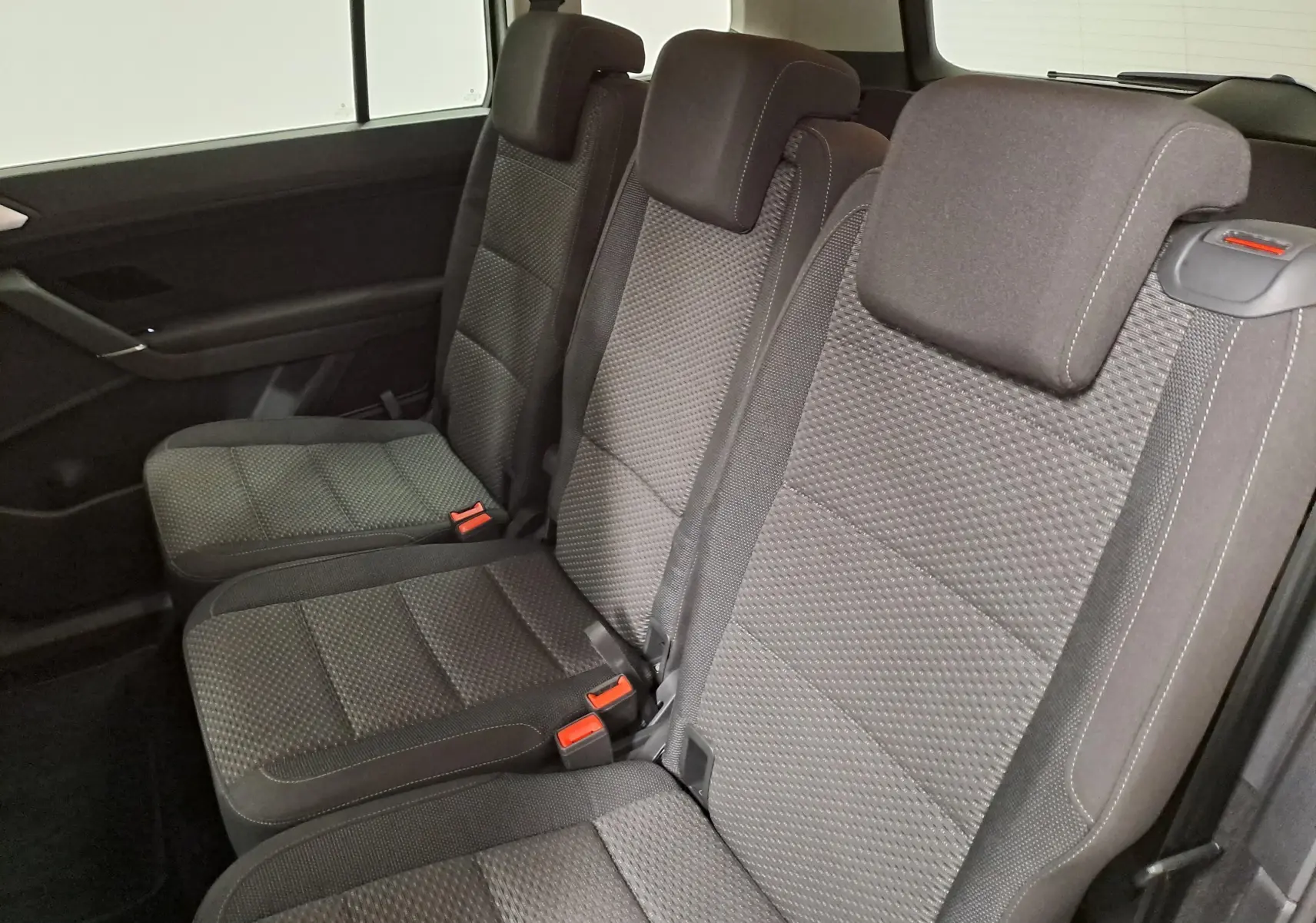 Vue intérieure sur les sièges arrière gris foncé du Volkswagen Touran 2025, version 7 places, avec ceintures et appuie-têtes visibles.