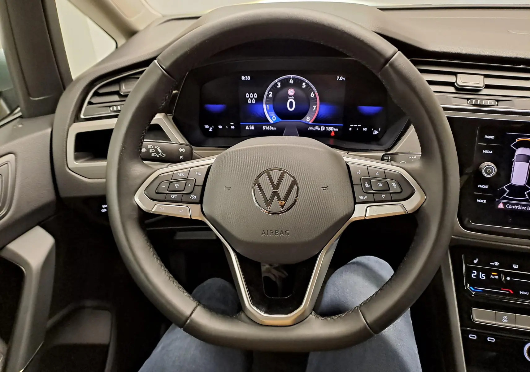 Vue intérieure centrée sur le volant noir du Volkswagen Touran 2025 avec tableau de bord numérique et écran tactile.