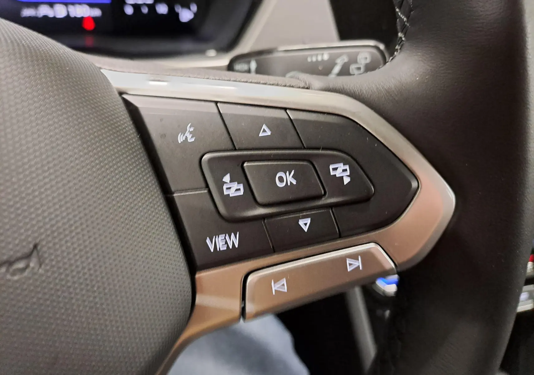 Gros plan sur les commandes multifonctions au volant côté gauche du Volkswagen Touran 2025 en Argent Dolomite.