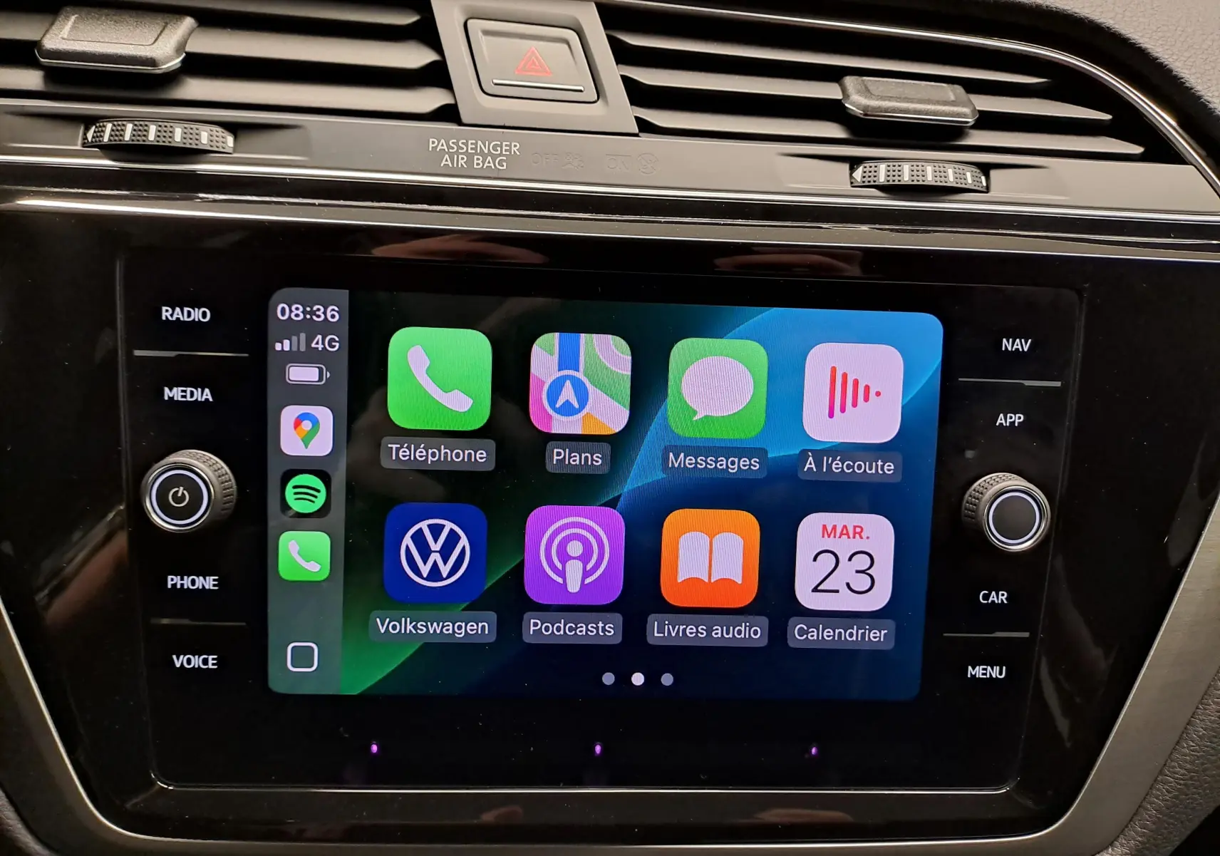 Écran tactile central du Volkswagen Touran 2025 affichant Apple CarPlay avec icônes colorées, entouré de commandes noires.