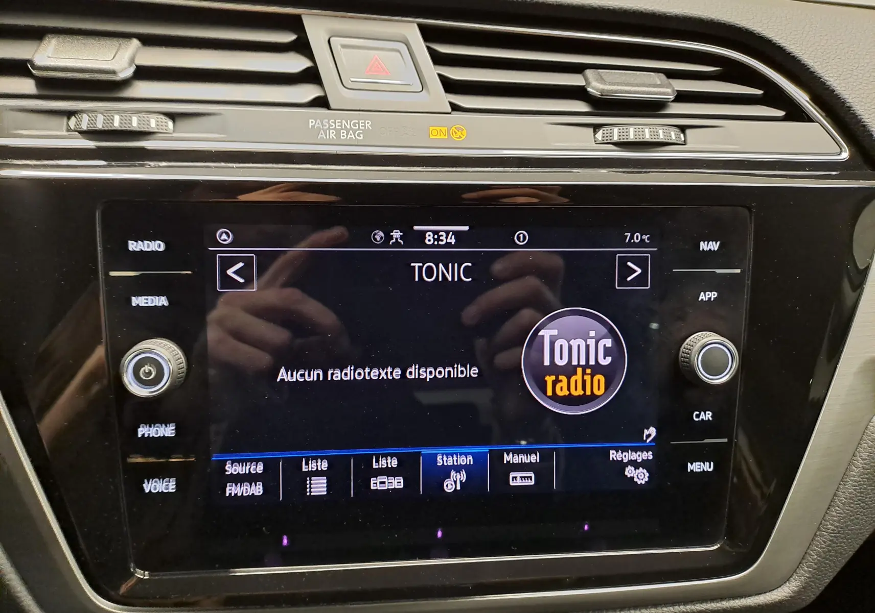 Écran tactile central du Volkswagen Touran 2025 affichant la radio Tonic, entouré de commandes noires et grises.