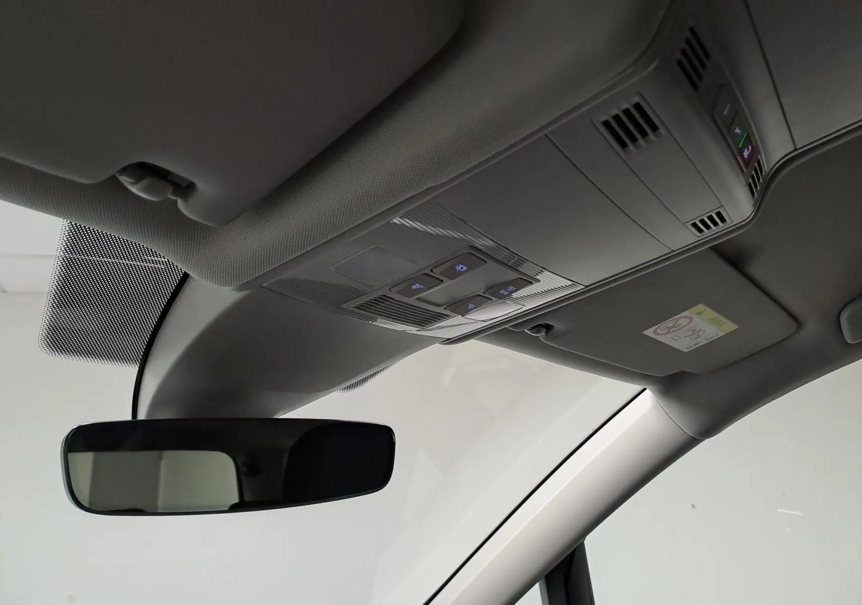 Vue intérieure du plafond avant du Volkswagen Touran 2025, montrant le rétroviseur et les commandes d'éclairage intégrées au plafonnier.