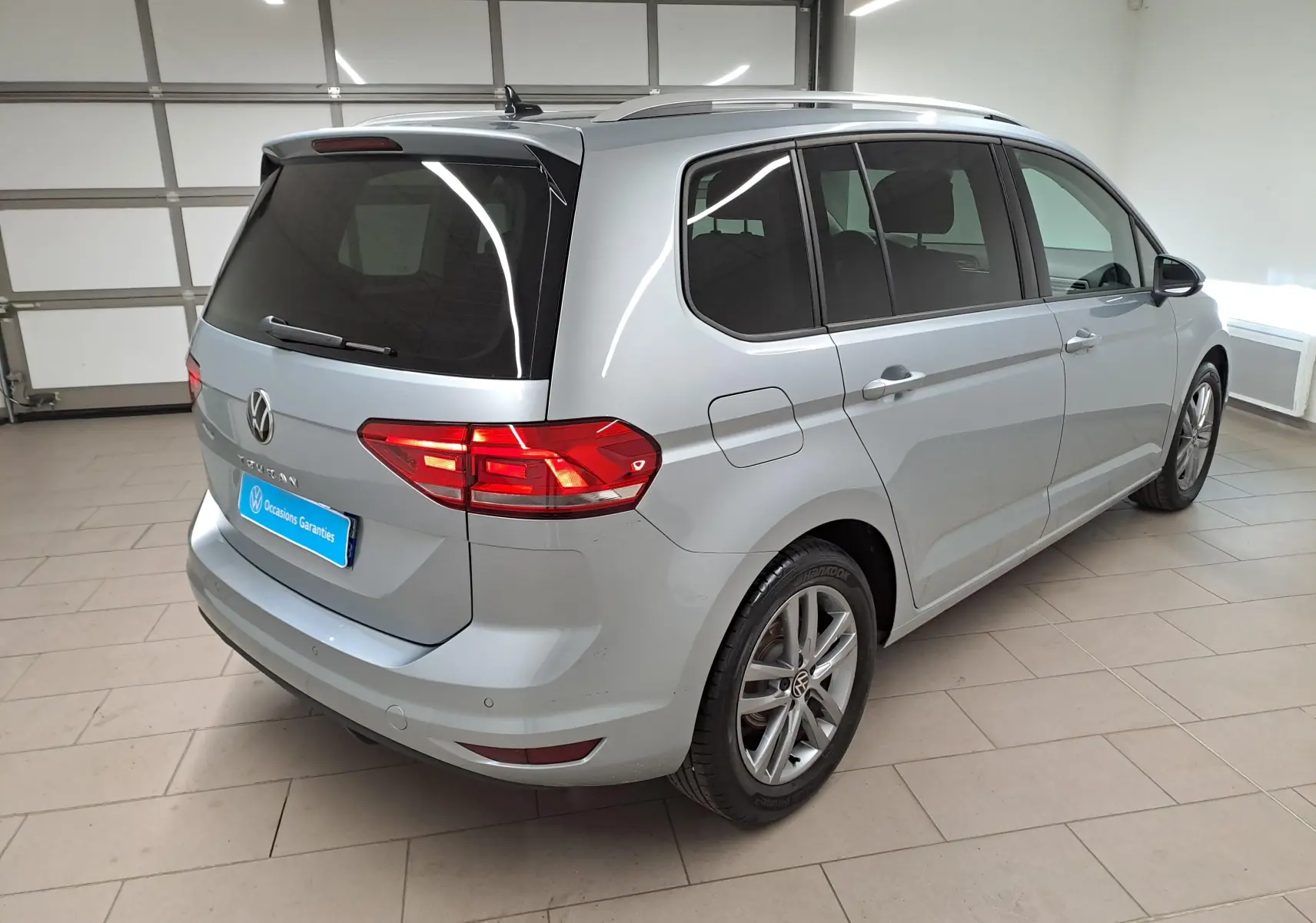 Volkswagen Touran 2025 argent Dolomite en vue 3/4 arrière droit, avec vitres teintées et jantes alliage.
