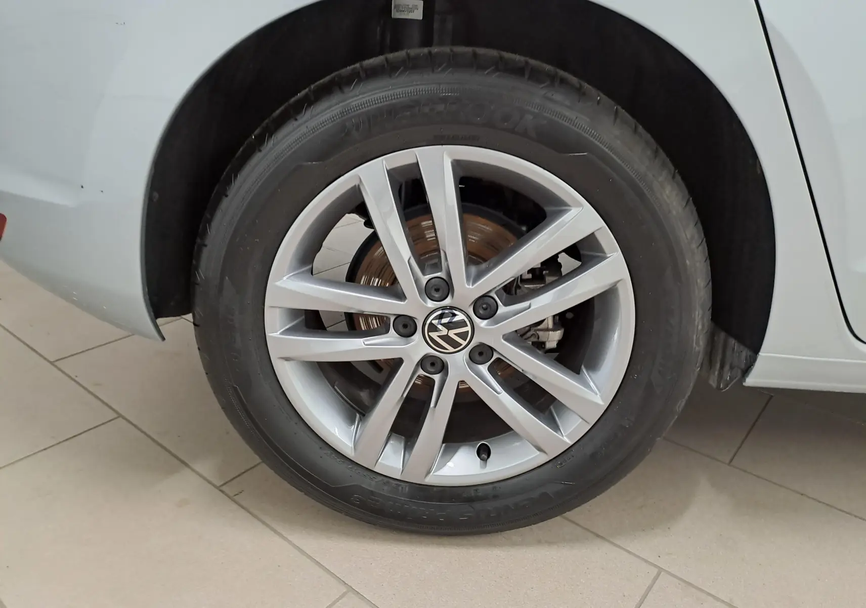 Gros plan sur la roue avant droite argentée du Volkswagen Touran 2025 avec jante alliage et peinture métallisée Argent Dolomite.