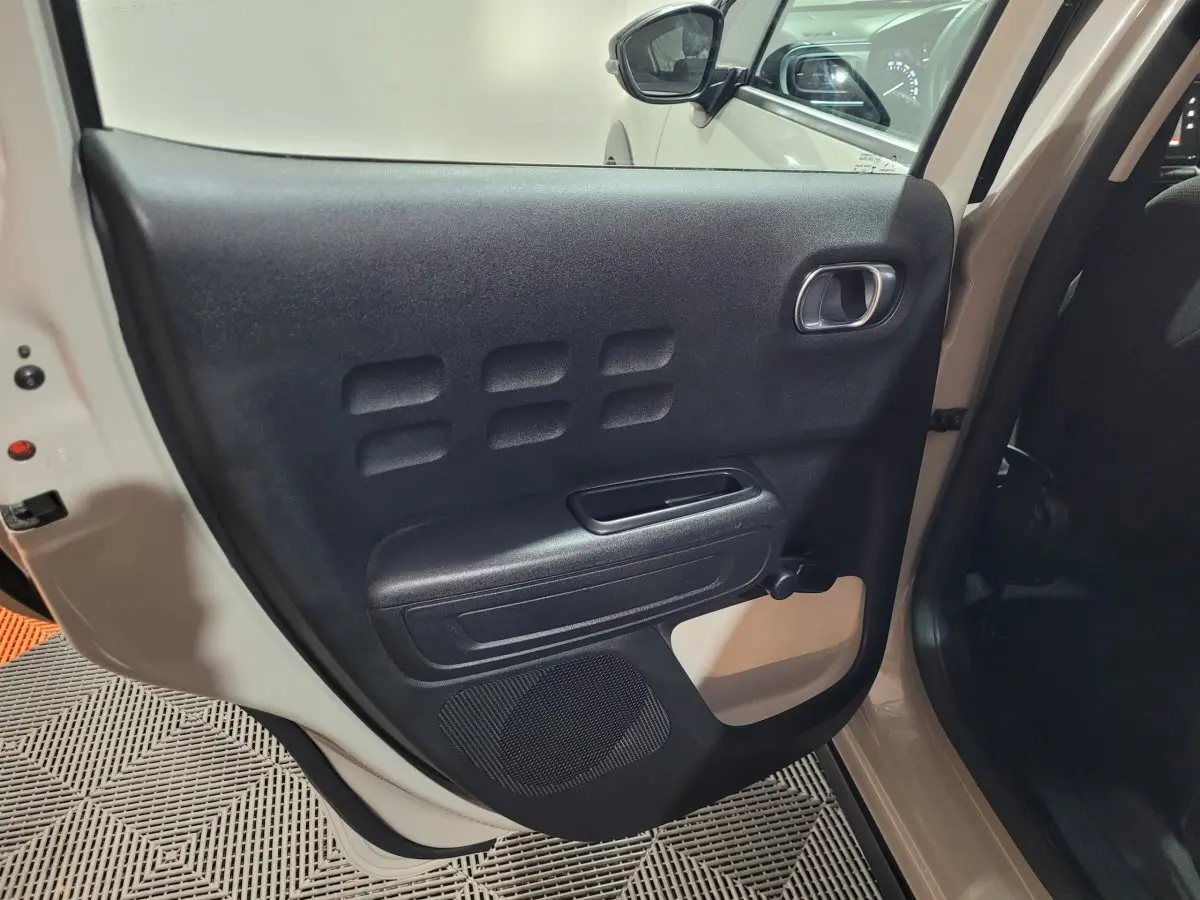 Vue intérieure de la porte arrière gauche beige d'une Citroën C3 2022 avec poignée et haut-parleur intégrés.