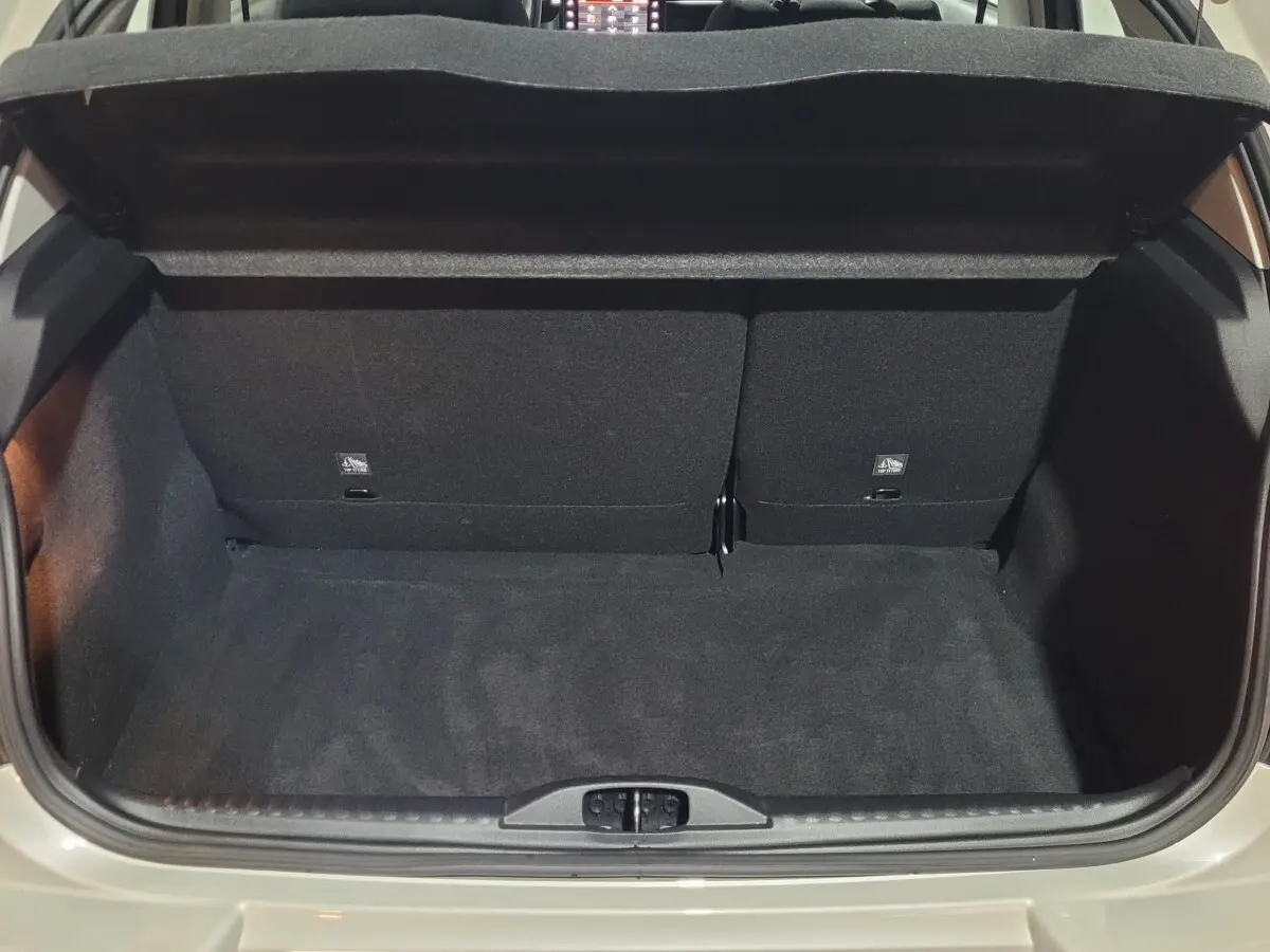 Coffre ouvert vu de l'arrière d'une Citroën C3 beige 2022, montrant l'espace de chargement avec banquette rabattue partiellement.