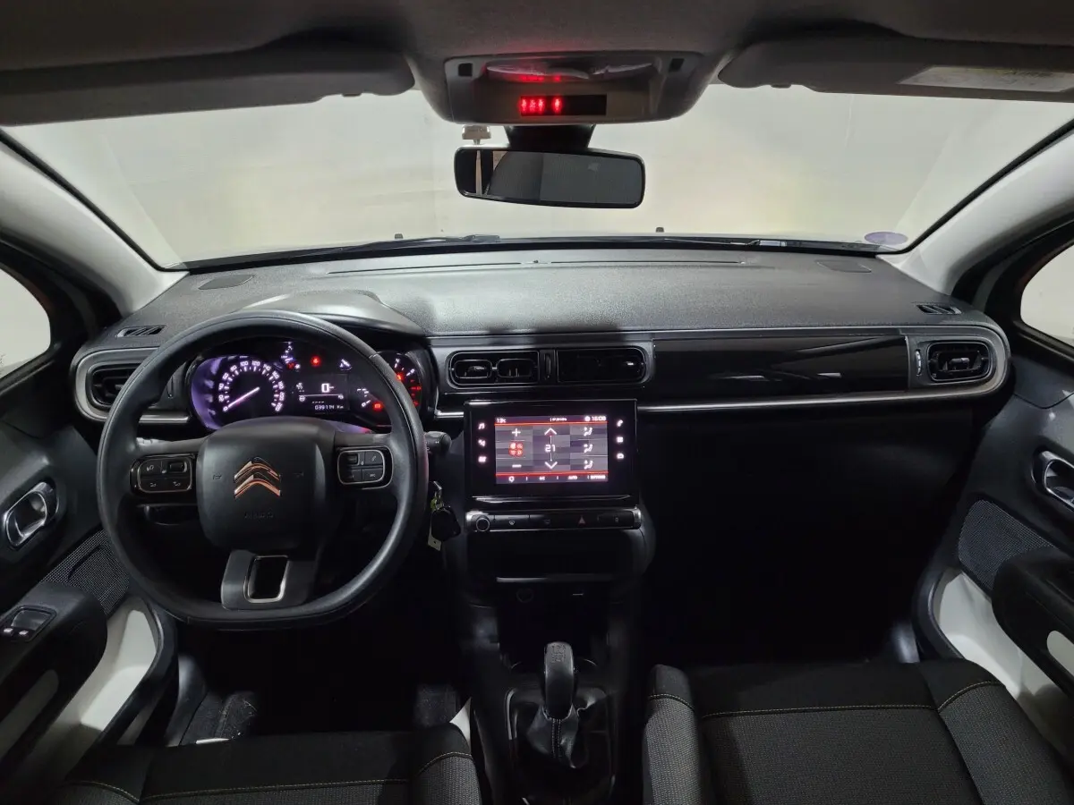 Vue intérieure avant de la Citroën C3 beige 2022, tableau de bord noir avec écran tactile central et volant multifonctions.