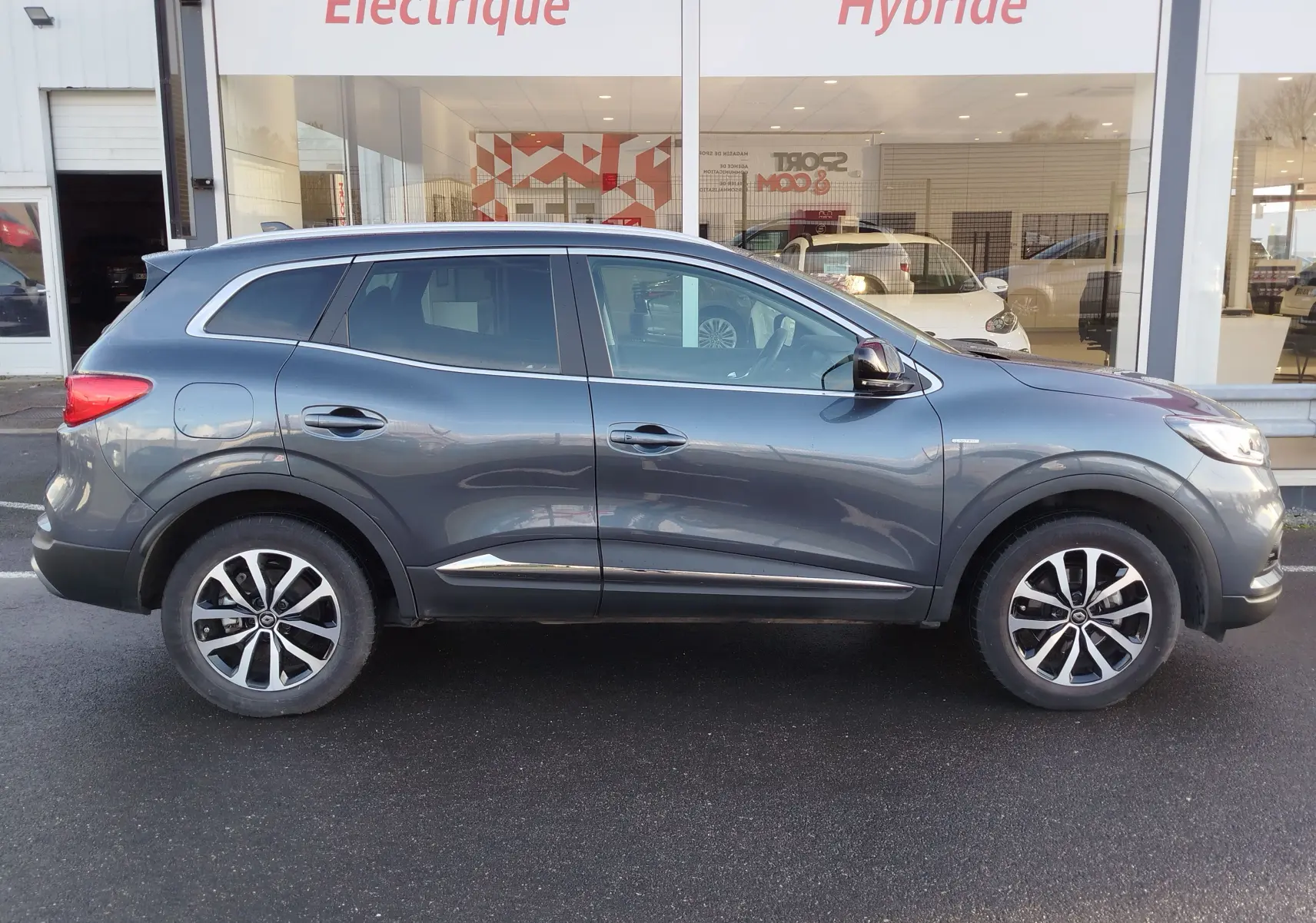 Profil côté droit d'un Renault Kadjar gris titanium 2021, avec jantes bi-ton et lignes de chrome sur les portières.