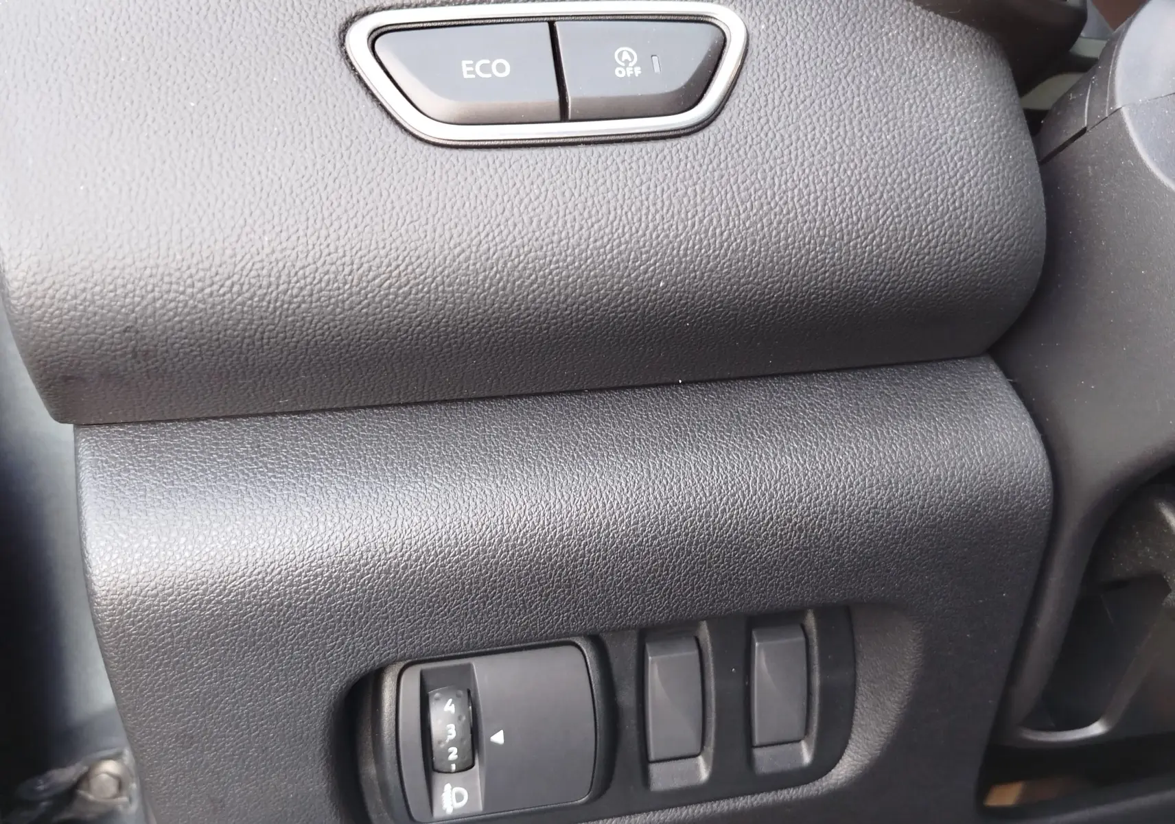 Détail intérieur du tableau de bord côté conducteur du Renault Kadjar 2021, boutons ECO et réglage des phares visibles.