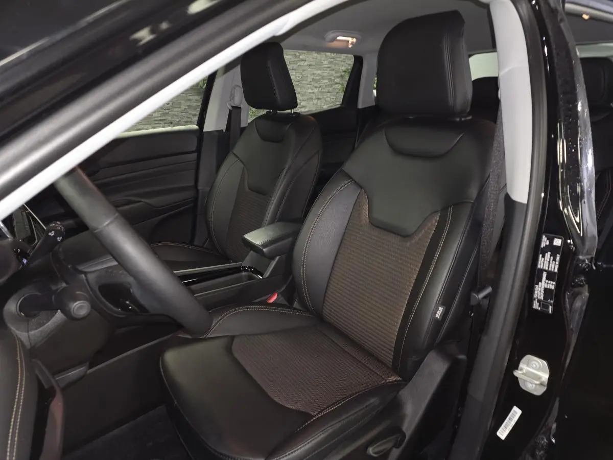 Vue intérieure côté conducteur du Jeep Compass 2024 noir, sièges avant en cuir et tissu noir avec surpiqûres bronze.