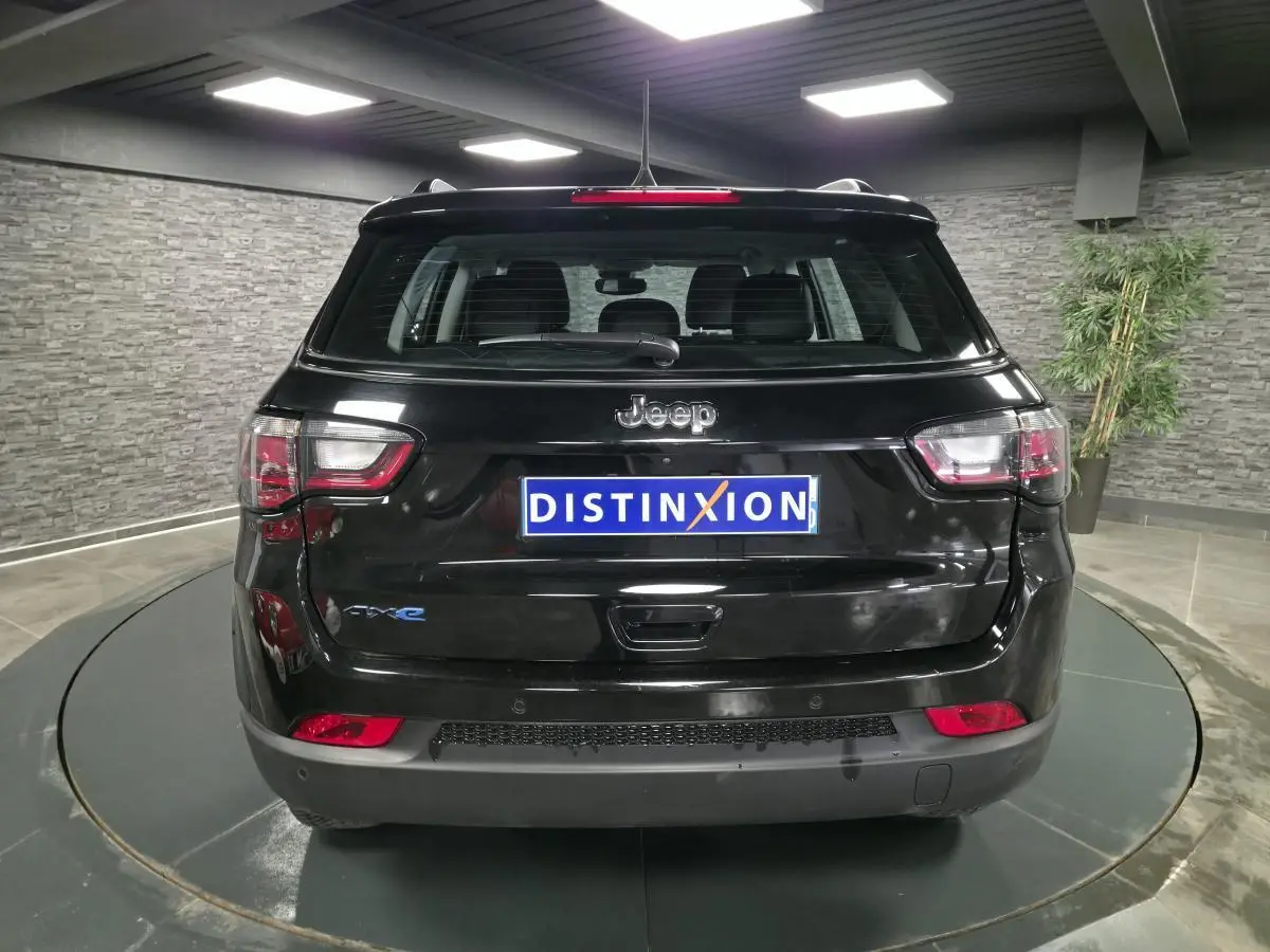 Vue arrière d'un Jeep Compass noir 2024 avec logo 4xe et feux arrière LED dans un showroom.