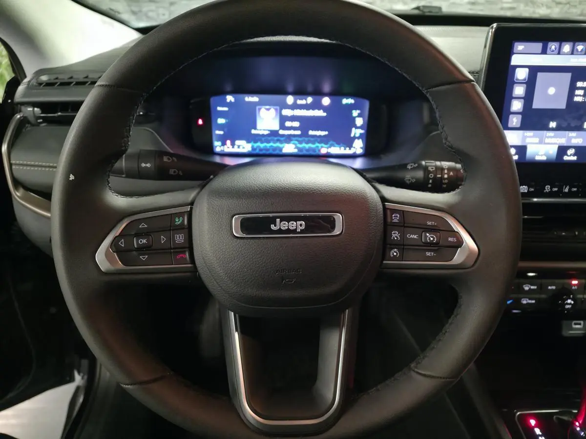 Volant cuir noir Jeep Compass 2024 vu de face avec commandes intégrées et tableau de bord numérique lumineux.