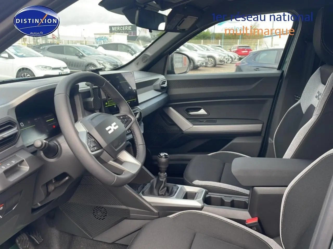 Vue intérieure côté conducteur du Dacia Duster 2026 vert cèdre, avec volant multifonction et boîte manuelle visible.