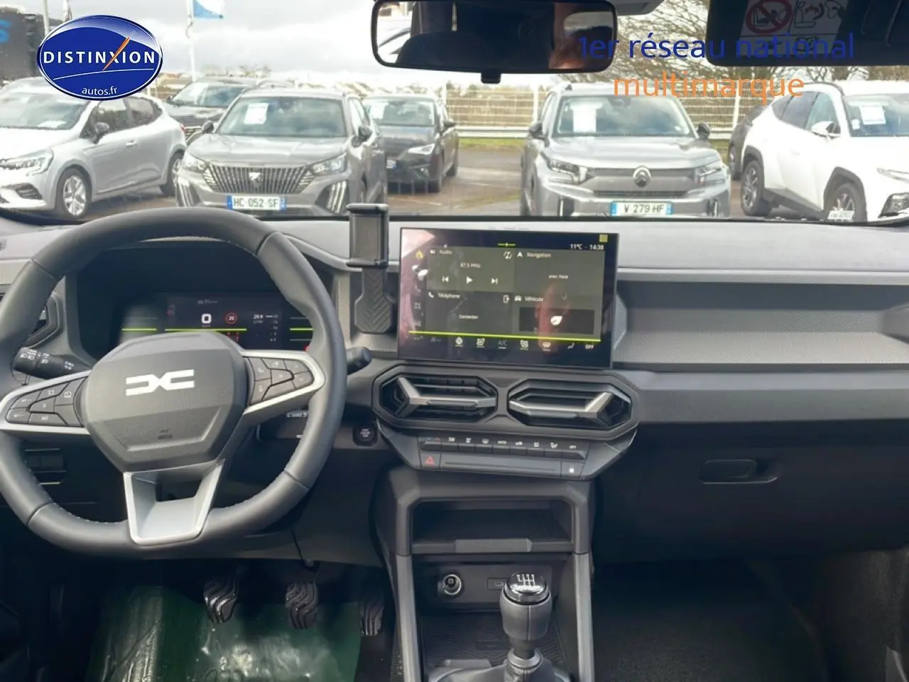 Tableau de bord et volant du Dacia Duster 2026 vert cèdre, vue frontale intérieure avec écran tactile et boîte manuelle.