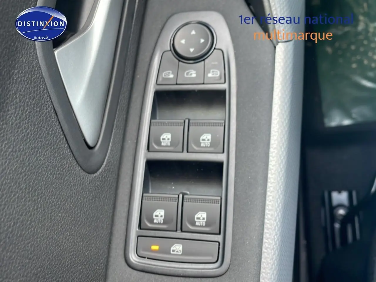 Gros plan sur les commandes des vitres électriques côté conducteur d'un Dacia Duster 2026, intérieur noir.