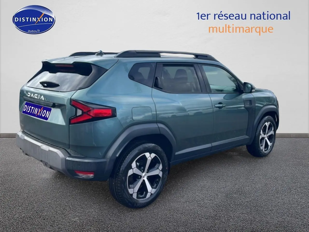 Vue 3/4 arrière droite du Dacia Duster 2026 vert cèdre avec jantes alliage et barres de toit visibles.