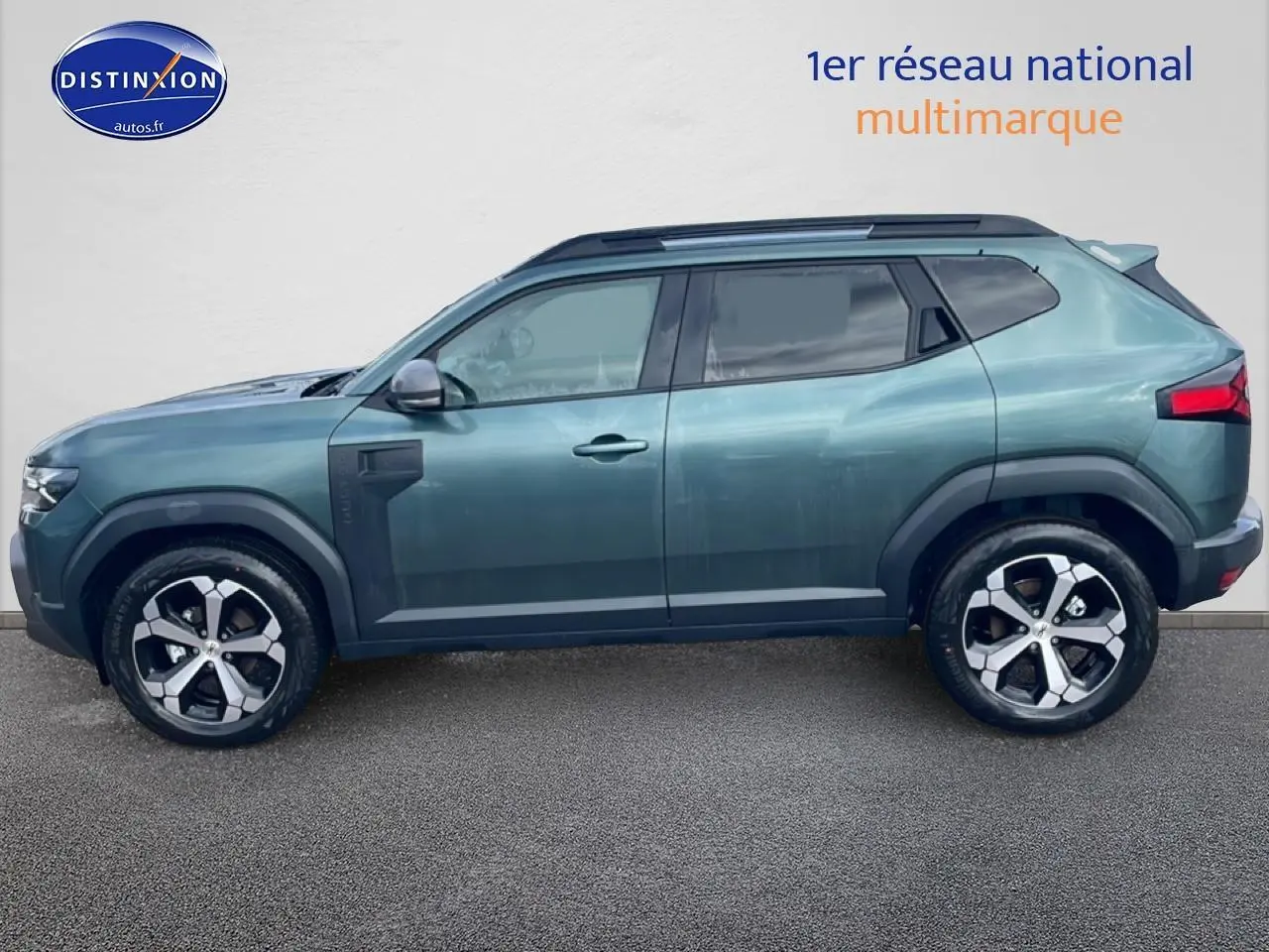 Profil droit du Dacia Duster 2026 vert cèdre avec jantes alu et barres de toit noires visibles.