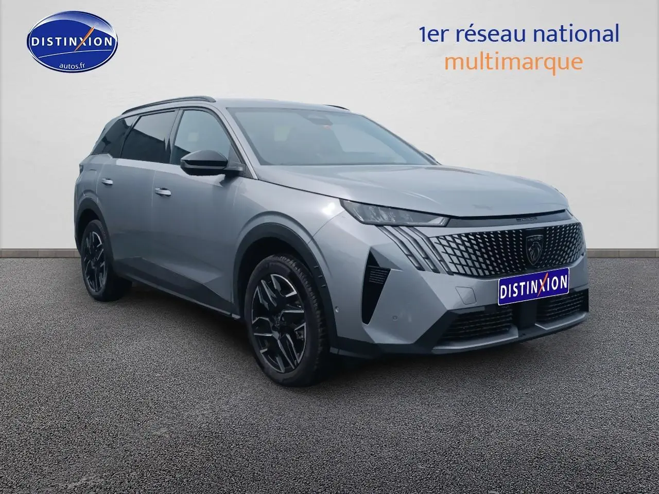 Peugeot 5008 gris artense en 3/4 avant droit, avec calandre distinctive et jantes alu noires.