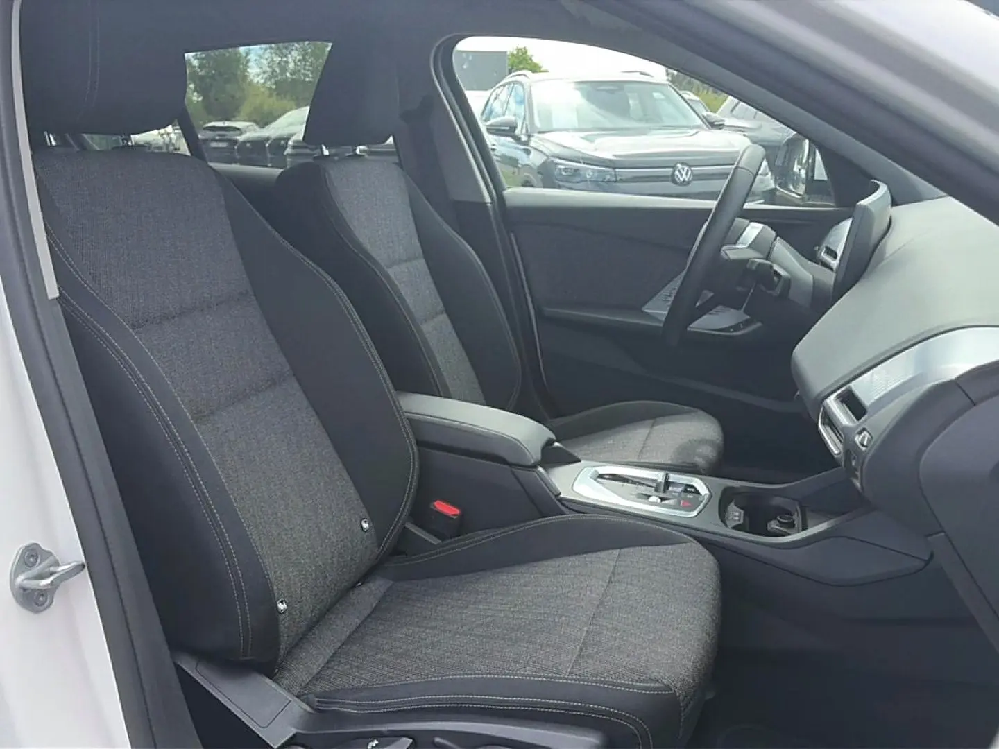 Vue intérieure côté conducteur de la BMW Série 1 blanche, sièges sport gris et console centrale avec boîte auto.