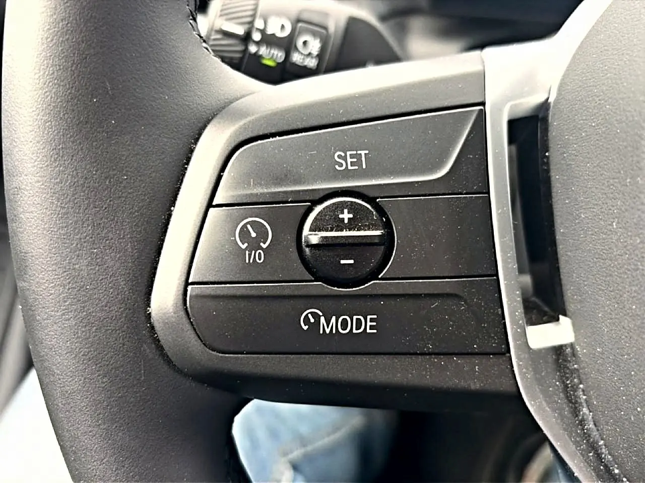 Gros plan sur les commandes de régulateur de vitesse au volant cuir noir d'une BMW Série 1 blanche.
