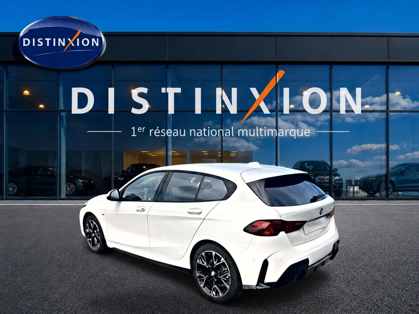 BMW Série 1 blanche vue en 3/4 arrière droit, avec jantes sport noires et vitres teintées, devant un showroom Distinxion.